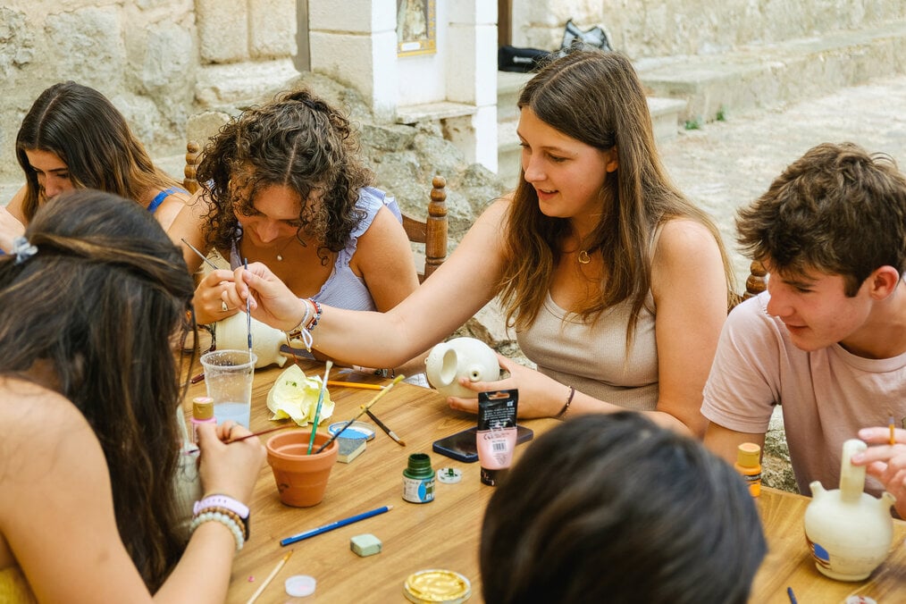 A group of teens paint pottery.